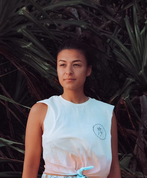 Sabrina, founder of Talaya Wellness, standing in front of palm leaves